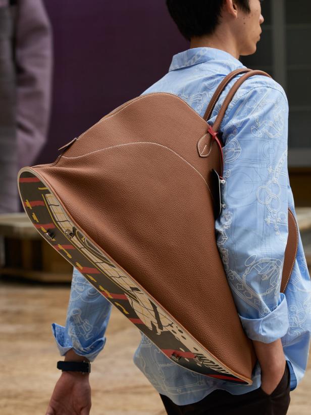 Ein Mann trägt eine braune Ledertasche mit Skateboard-Motiv über der Schulter.