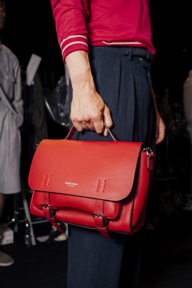 Eine Person hält eine rote Giorgio Armani Handtasche.