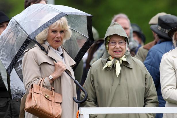 Königin Elisabeth II. und Camilla, die Herzogin von Cornwall, unter einem Regenschirm.