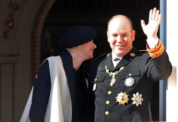 Fürst Albert II. von Monaco und Fürstin Charlène winken von einem Balkon.