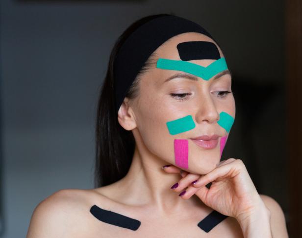 Eine Frau mit Kinesio-Tape im Gesicht und auf den Schultern trägt ein Stirnband.