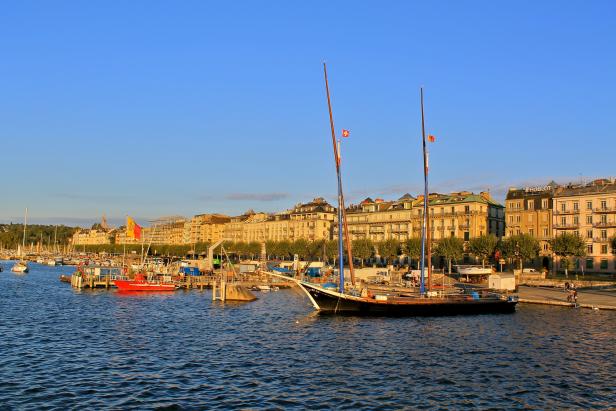 Blick auf den Hafen von Genf mit Booten und Gebäuden im Hintergrund.