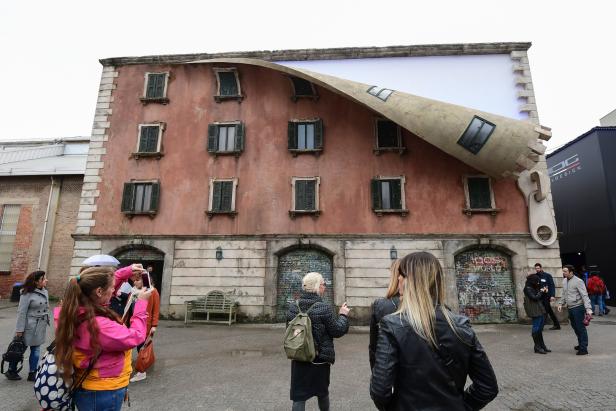 Ein Gebäude, dessen Fassade wie ein aufgerollter Vorhang mit einem Reißverschluss aussieht.