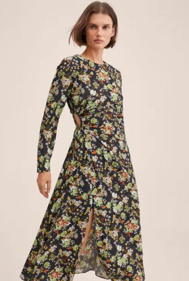 Eine Frau trägt ein langärmeliges, blumengemustertes Kleid mit Schlitz.