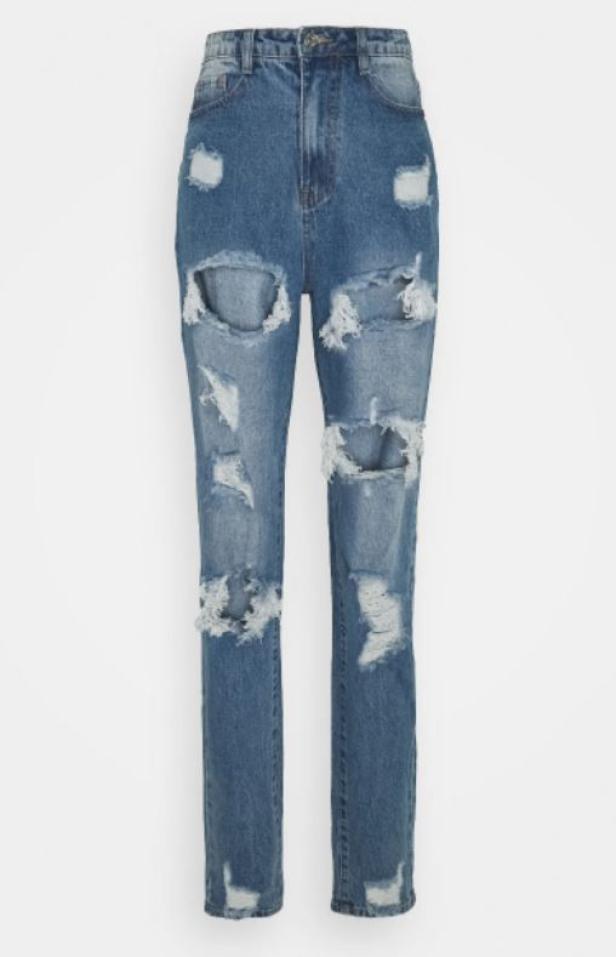 Eine blaue Jeans mit vielen Rissen liegt vor einem weißen Hintergrund.