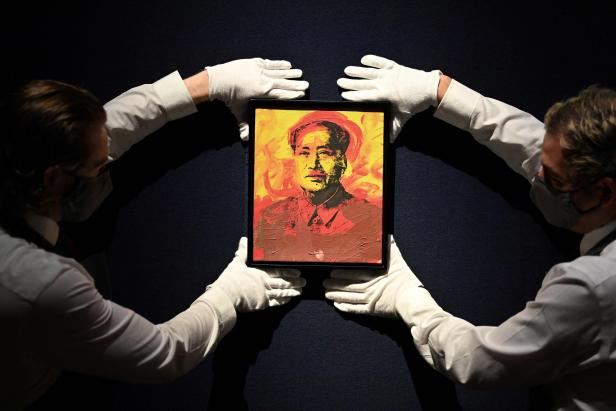 Zwei Personen mit Handschuhen halten ein Gemälde von Mao Zedong.