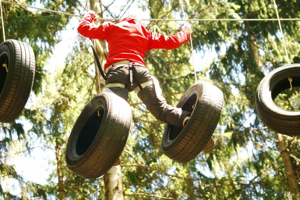 Eine Person balanciert auf einem Hindernisparcours zwischen hängenden Reifen.