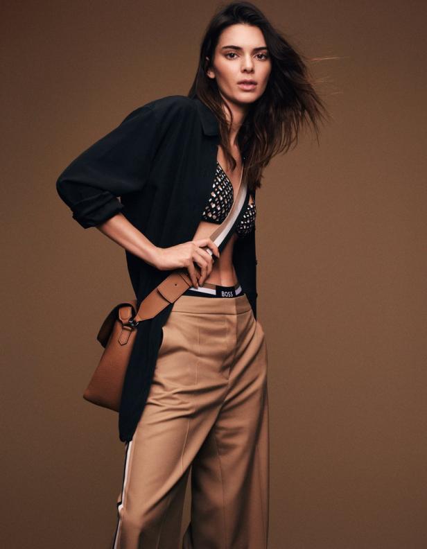 Kendall Jenner posiert mit einer braunen Handtasche und beigen Hosen für eine BOSS-Kampagne.