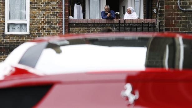 Ein älteres Paar schaut aus dem Fenster über einem roten Ferrari.