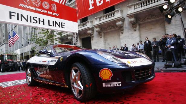 Ein blau-weißer Ferrari steht auf einem roten Teppich unter einem „Finish Line“-Banner.