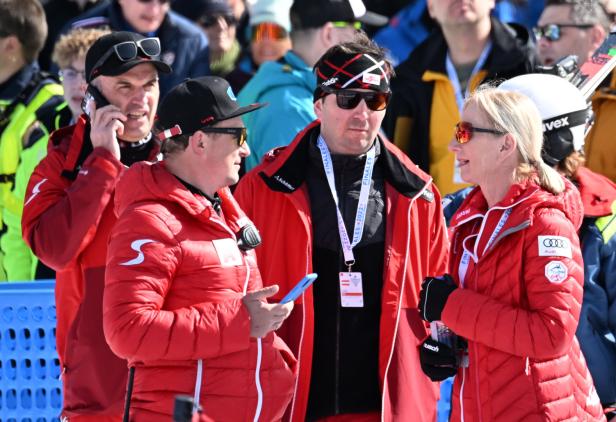 Eine Gruppe von Personen in roten Jacken unterhält sich im Freien.