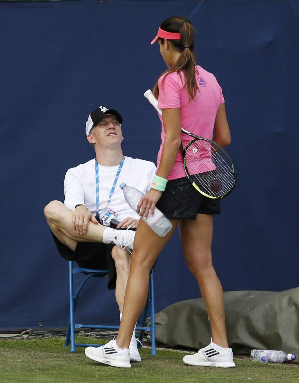 Ein Tennisspieler sitzt auf einem Stuhl, während eine Tennisspielerin neben ihm steht.