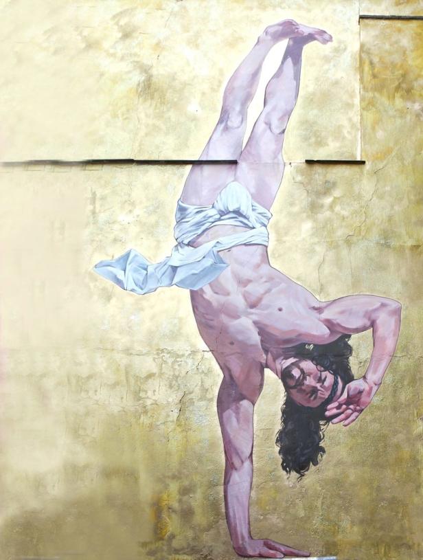 Ein Gemälde zeigt einen Mann in einem weißen Tuch, der einarmig einen Handstand macht.