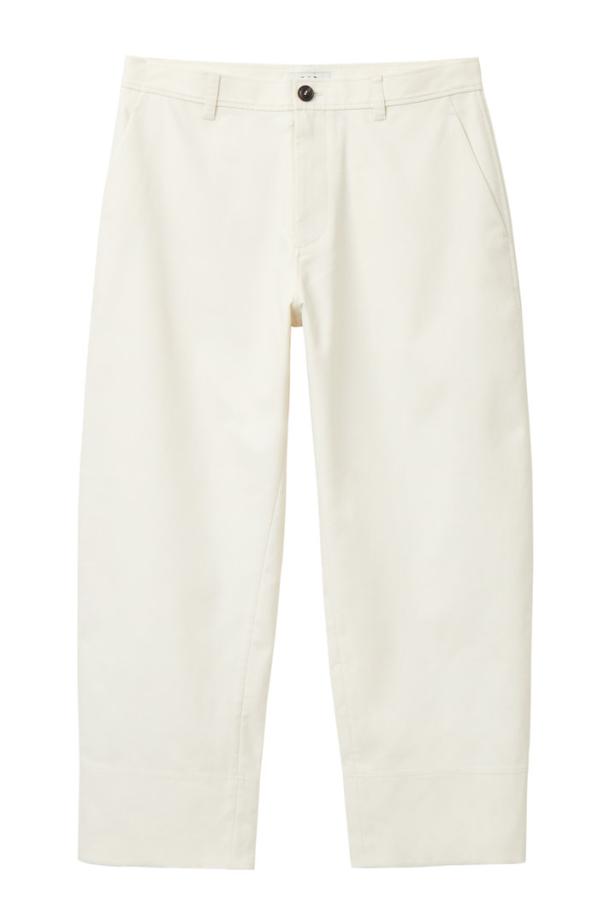 Eine weiße Stoffhose mit weitem Bein vor einem weißen Hintergrund.