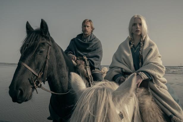 Anya Taylor-Joy und Alexander Skarsgård reiten in „The Northman“ auf Pferden am Strand.