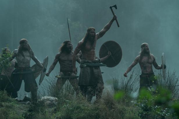 Eine Gruppe von Wikingern steht mit Äxten und Schilden bereit für den Kampf.
