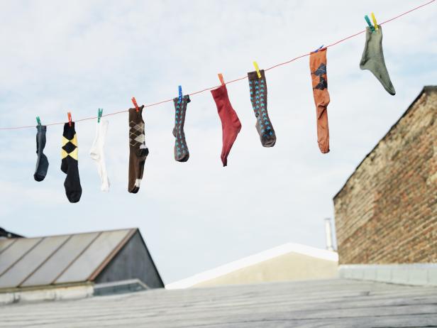 Mehrere Socken hängen an einer Wäscheleine auf einem Dach.