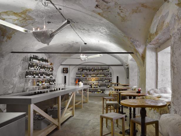 Innenansicht einer Weinbar mit Regalen voller Weinflaschen und Tischen für Gäste.