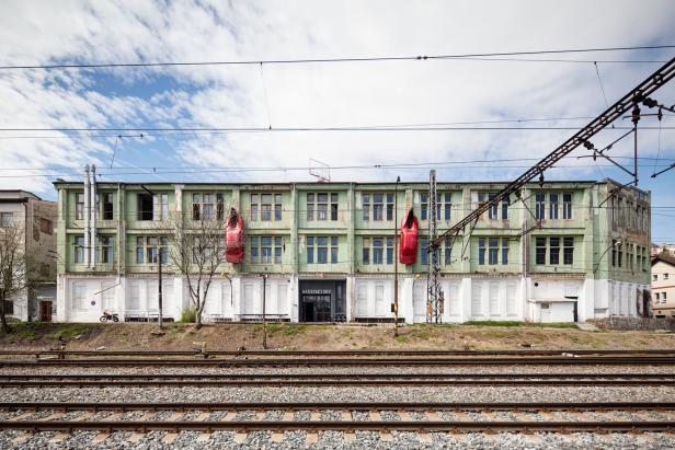 Die Fassade der MeetFactory in Prag mit zwei roten Autoskulpturen an der Wand.