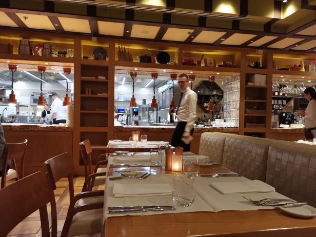 Ein gedeckter Tisch in einem Restaurant mit Blick auf die Küche und das Personal.