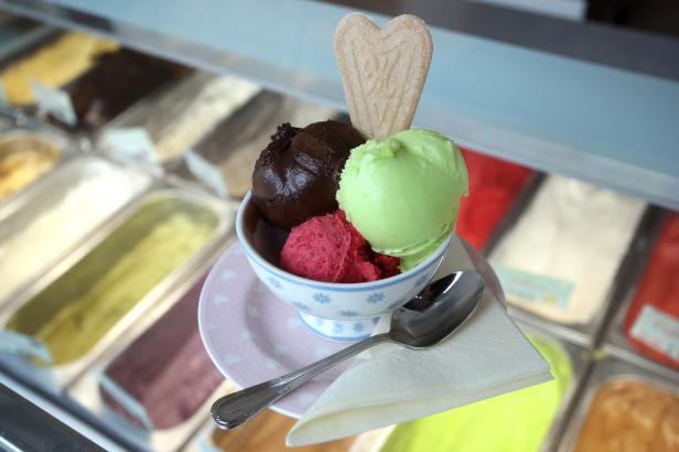 Ein Eisbecher mit drei Kugeln Eis und einem herzförmigen Keks steht bereit.