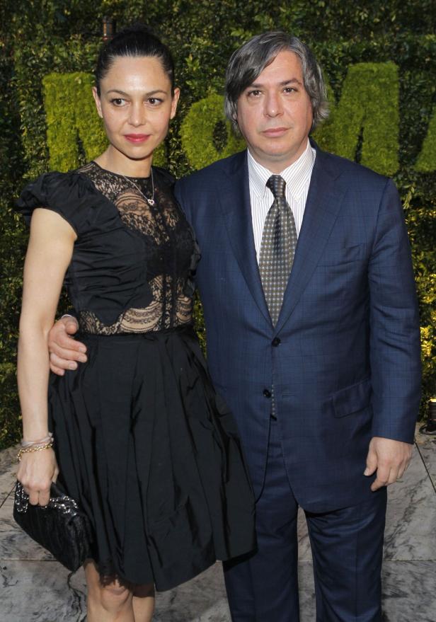 Anna and George Condo attend the Museum of Modern Eine Frau in einem schwarzen Kleid und ein Mann im Anzug posieren vor einer grünen Wand.