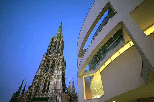 Das Ulmer Münster und ein modernes Gebäude unter blauem Himmel.
