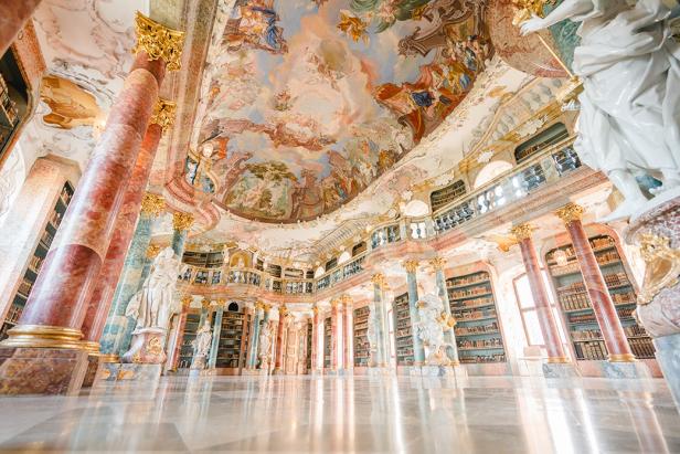 Die Stiftsbibliothek Admont mit ihren hohen Bücherregalen und dem kunstvollen Deckengemälde.