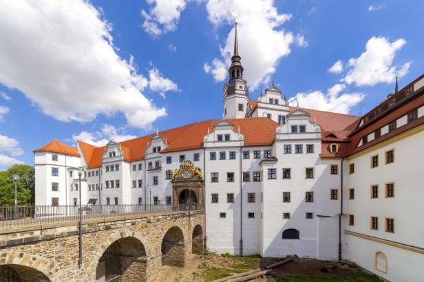 Schloss Hartenfels in Torgau mit einer Steinbrücke im Vordergrund.