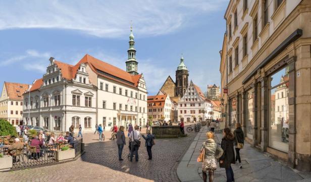 Blick auf den Marktplatz von Torgau mit historischen Gebäuden und Passanten.