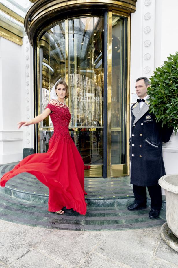 Eine Frau im roten Kleid vor dem Hotel Imperial mit einem Portier.