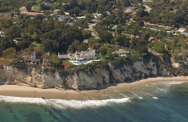 Ein großes Haus mit Pool thront auf einer Klippe über dem Meer.
