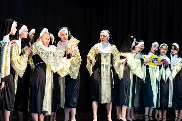 Eine Gruppe von Frauen in Nonnenkostümen steht auf einer Bühne.