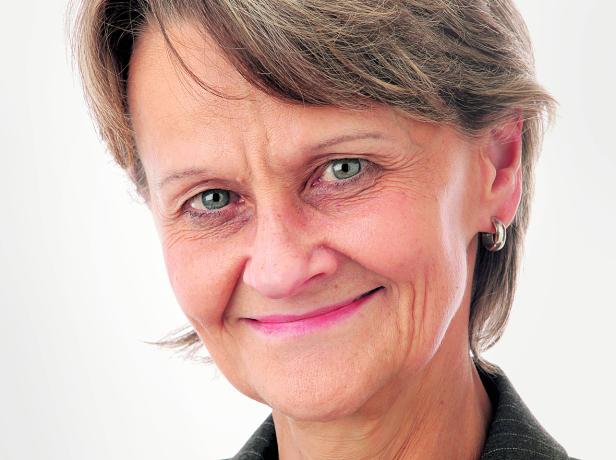 Porträt einer lächelnden Frau mit kurzem, grauem Haar und blauen Augen.