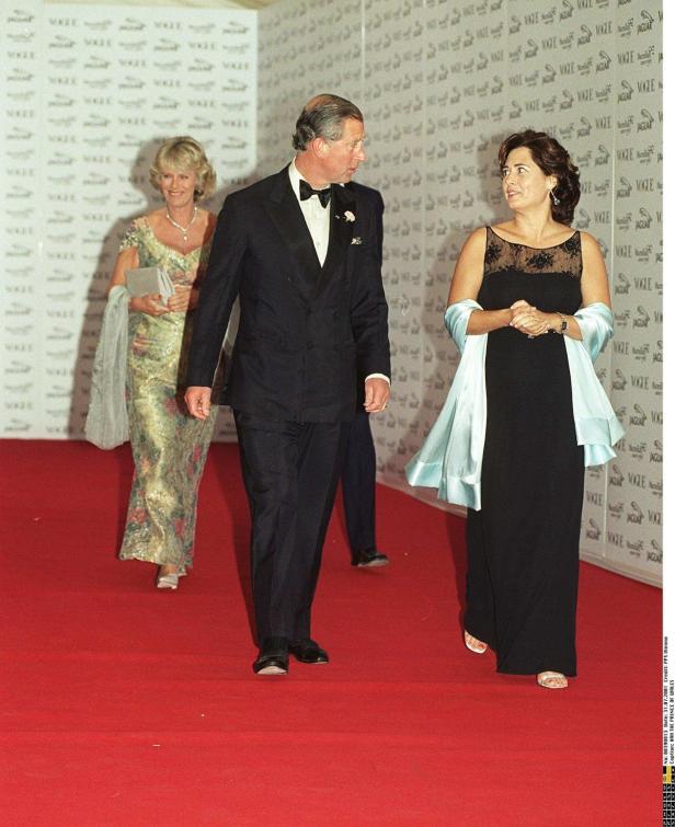 Prinz Charles in einem Smoking mit zwei Damen auf einem roten Teppich.