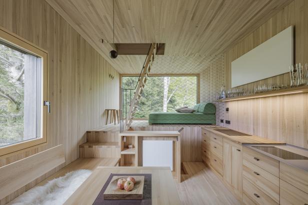 Innenansicht eines modernen Holzhauses mit Küche, Treppe und Blick ins Grüne.