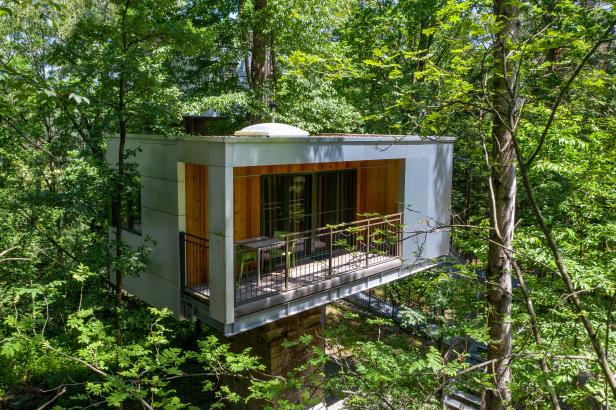 Ein modernes Baumhaus mit Balkon inmitten von dichtem Grün.