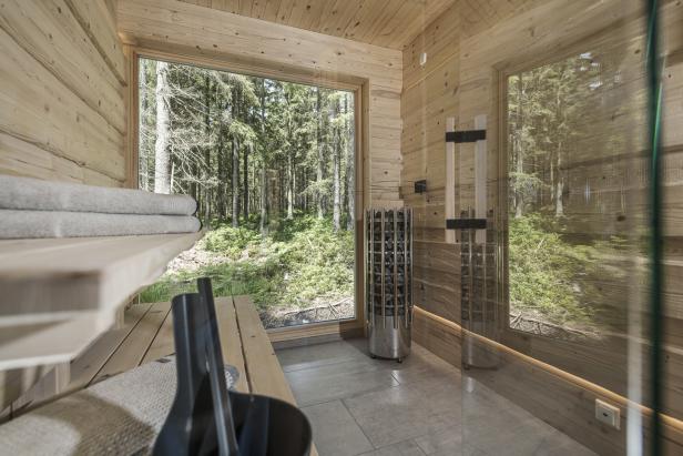 Eine Sauna mit Holzwänden und Blick auf einen dichten Wald.