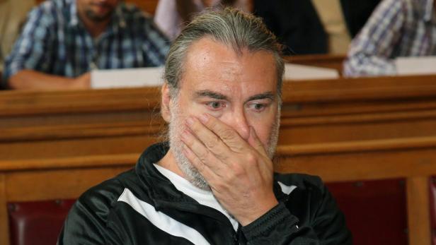 Ein Mann mit Bart hält seine Hand vor das Gesicht.