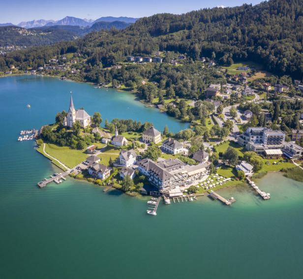 Luftaufnahme von Maria Wörth am Wörthersee mit Bergen im Hintergrund.