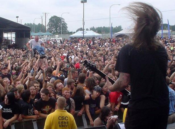 Ein Mann im Rollstuhl wird auf einem Konzert von der Menge hochgehoben.