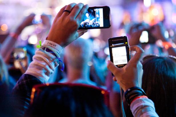 Menschen fotografieren mit ihren Handys eine Veranstaltung.