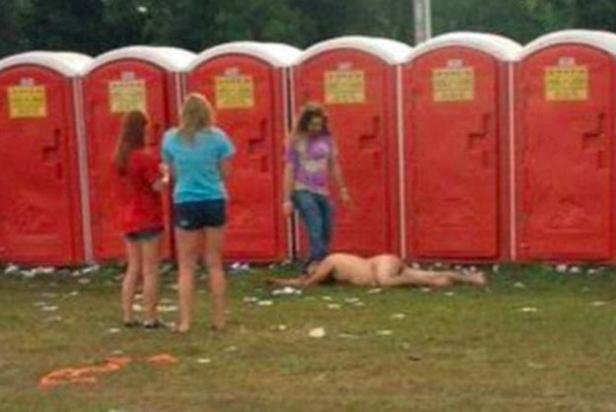 Mehrere Personen und eine bewusstlose Person vor einer Reihe roter, tragbarer Toiletten.