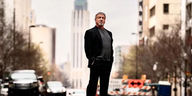Sylvester Stallone steht auf einer Straße in der Stadt.
