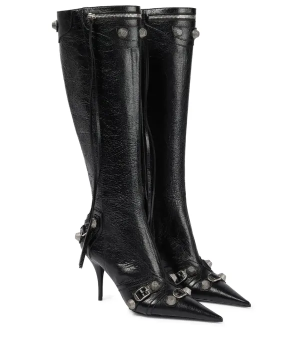Ein Paar schwarze, kniehohe Stiefel mit Nieten und Schnallen stehen vor einem weißen Hintergrund.