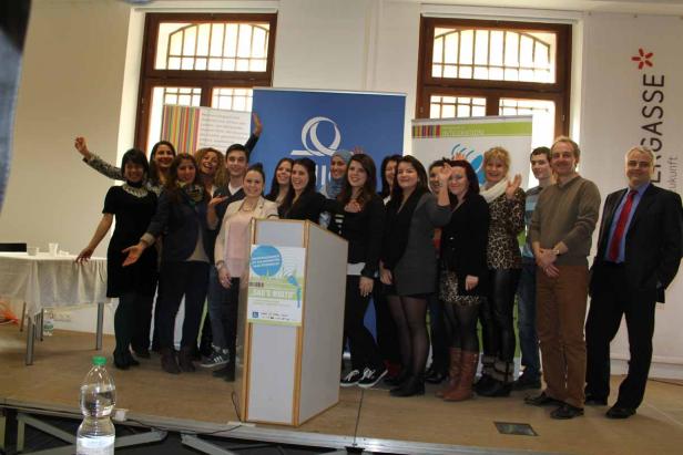 Eine Gruppe von Menschen steht auf einer Bühne hinter einem Rednerpult.