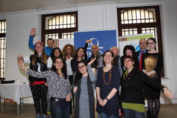 Eine Gruppe von Menschen posiert lächelnd vor einem Banner.