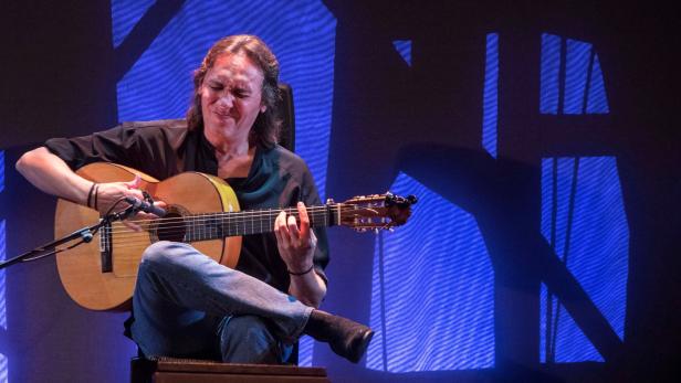 Ein Mann spielt mit geschlossenen Augen Gitarre auf einer Bühne.