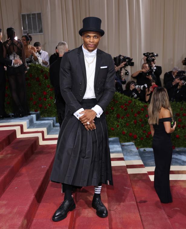 Russell Westbrook in einem schwarzen Anzug mit Zylinder und Rock auf dem roten Teppich.