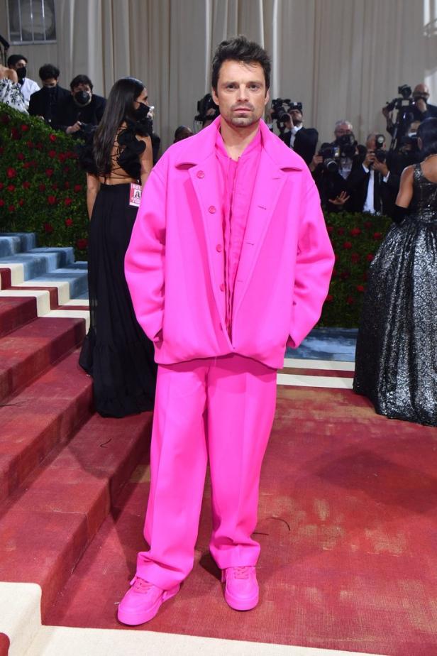 Sebastian Stan in einem komplett pinken Anzug auf einem roten Teppich.